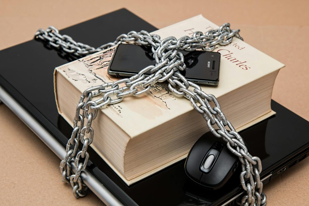 Intellectual Property Registration & Protection Chain-locked book, phone, and laptop symbolizing digital and intellectual security.
