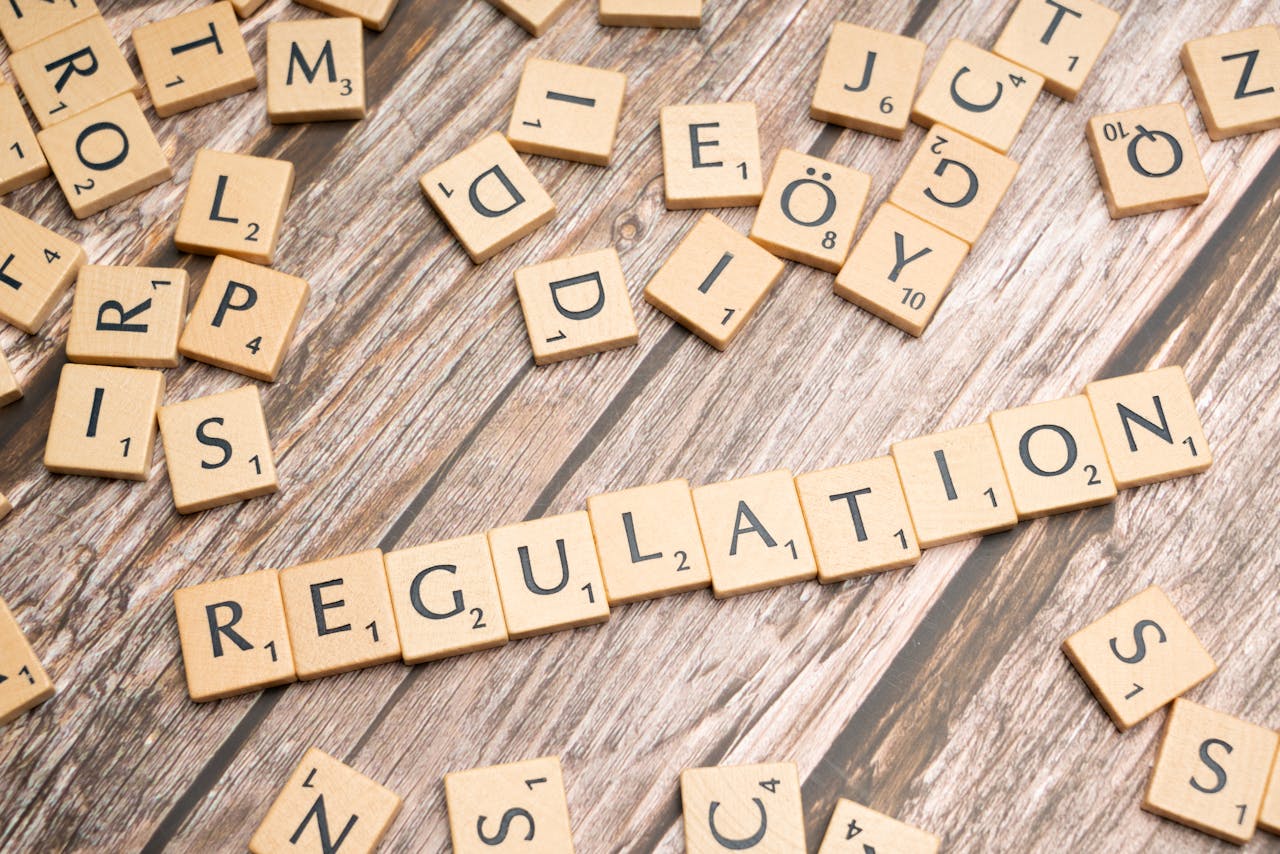 Regulatory Advisory Wooden letter tiles spelling 'Regulation' on a textured wood background, conveying themes of compliance and structure.